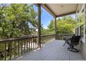 Relaxing covered deck with outdoor seating surrounded by lush green trees and a distant view at 9873 Greensview Cir, Lone Tree, CO 80124