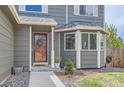 Close up of the front entrance with a wreath, flowerbeds, bay window, and well manicured lawn at 1521 Redtail Ct, Longmont, CO 80504