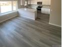 Open-concept kitchen featuring gray wood floors, white cabinetry and a center island at 521 10Th St, Fort Lupton, CO 80621