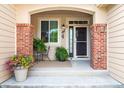 Inviting front porch with brick accents, a decorative window, and space for seating and potted plants at 1026 Deer Clover Way, Castle Pines, CO 80108