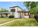 Charming two-story home with painted brick, black trim, balcony, and a well-manicured lawn at 3550 Eudora St, Denver, CO 80207