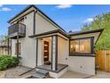 A modern home has a painted brick exterior with black trim and a balcony overlooking the front yard at 3550 Eudora St, Denver, CO 80207