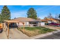 Inviting single-story home featuring a carport, covered porch, and well-maintained lawn, bathed in sunlight at 724 Ursula St, Aurora, CO 80011
