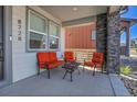 Cozy front porch featuring comfortable orange seating, a small table, and stone pillar accents at 8728 Hotchkiss St, Littleton, CO 80125