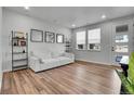 Bright living room with wood floors, large windows, and a stylish white couch for comfortable living at 8728 Hotchkiss St, Littleton, CO 80125