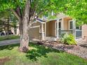 Inviting home exterior with well-maintained lawn, mature tree, and covered front porch at 4111 W Kenyon Ave, Denver, CO 80236