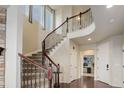 Grand foyer with a curved staircase featuring wood banisters and wrought iron spindles at 7099 E 123Rd Pl, Thornton, CO 80602