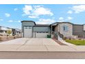 Charming home with a gray exterior, well-manicured lawn, a stone facade, and a spacious driveway at 5385 Trails Edge Ln, Castle Rock, CO 80104