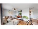 Cozy living room with a sectional sofa, stylish decor, ceiling fan and hardwood flooring throughout the home at 10759 Clermont St, Thornton, CO 80233