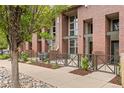 Brick condo building with metal accents and front patios surrounded by lush, manicured landscaping at 7700 E 29Th Ave # 102, Denver, CO 80238