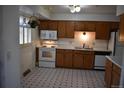 Functional kitchen with wooden cabinetry, white appliances, and checkered flooring, a practical space for cooking at 14702 E Security Way, Aurora, CO 80011