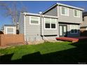 View of the home's backyard with a small red deck and shed surrounded by lush lawn and mature landscape at 292 S Pembrook St, Castle Rock, CO 80104