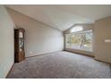 Large, carpeted living room featuring a large window, neutral colored walls, and a vaulted ceiling at 292 S Pembrook St, Castle Rock, CO 80104