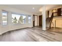 Bright living room featuring new light wood flooring, a large bay window, and a staircase at 11892 Vallejo St, Denver, CO 80234