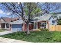 Charming two-story home featuring a gray garage door, blue siding, brick accents, and a well-manicured lawn at 13777 W Amherst Way, Lakewood, CO 80228