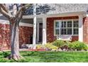 Inviting front porch with a cozy swing, red brick accents, and beautiful landscaping at 13777 W Amherst Way, Lakewood, CO 80228