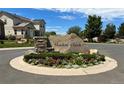 Well-maintained entrance to Shadow Creek neighborhood with stone signage and colorful flower beds at 22312 E Plymouth Cir, Aurora, CO 80016