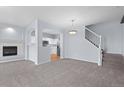 Open-concept living room with fireplace, kitchen view, and carpeted stairs to the upper level at 12711 Colorado Blvd # 1116, Thornton, CO 80241