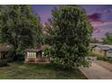 A cozy home is nestled among mature trees with a glimpse of the setting sun in the distance at 8525 Grandview Ave, Arvada, CO 80002
