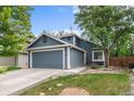 Charming blue two-story home featuring a two-car garage and lush front yard at 13341 Birch Cir, Thornton, CO 80241