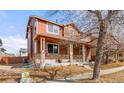 Corner lot home with a covered porch featuring stone accents, American flag, and well-maintained landscaping at 11034 Nome St, Commerce City, CO 80640