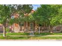 Charming two-story house with covered porch, stone accents, well-kept lawn, and mature trees at 11034 Nome St, Commerce City, CO 80640