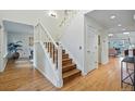Bright foyer featuring hardwood floors, a white staircase with wooden steps, and access to the living areas at 10849 E Crestridge Cir, Englewood, CO 80111