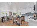 Modern kitchen with white cabinets, stainless steel appliances, and herringbone backsplash at 34 University Dr, Longmont, CO 80503
