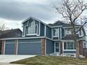 Two-story house with a gray exterior, brick accents, and a three-car garage at 245 Dunhill St, Castle Rock, CO 80104