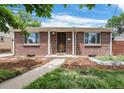 Charming brick home featuring a well-maintained front yard and a welcoming entryway under blue skies at 457 S Locust St, Denver, CO 80224