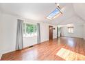 Bright living room with vaulted ceilings, wood floors, a skylight, and large windows offering ample natural light at 457 S Locust St, Denver, CO 80224