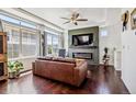 Cozy living room with fireplace, large windows, ceiling fan, and dark wood floors at 10560 Waco St, Commerce City, CO 80022
