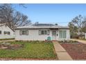 Charming single-story home featuring a quaint front yard with budding flowers and a walkway to the entrance at 1011 Uvalda St, Aurora, CO 80011