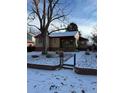 Charming single-story home featuring a brick facade, red roof, and snow-covered front yard with mature trees at 2060 S Washington St, Denver, CO 80210