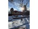 Charming single-story home with brick accents, and a red roof, surrounded by mature trees in a snow-covered yard at 2060 S Washington St, Denver, CO 80210