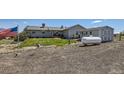 Exterior view of the home with a large yard, storage tank, American flag, and gravel ground cover at 7716 Shenandoah Dr, Elizabeth, CO 80107