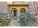 Inviting covered front porch with stone pillars and an arched entryway at 10631 Autumnsong Ct, Highlands Ranch, CO 80126
