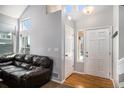 Bright entryway with hardwood floors, a brown leather sofa, and a staircase at 16277 Blueleaf Pl, Parker, CO 80134
