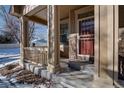 Inviting covered front porch with stone accents and a red door at 8588 W Quarles Pl, Littleton, CO 80128