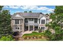 Back exterior featuring a stone facade, solar panels, a covered patio, a manicured lawn, and a wooden fence at 4944 W 107Th Loop, Westminster, CO 80031