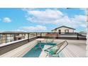 Relaxing roof deck boasts outdoor seating and scenic views under a bright blue sky with fluffy white clouds at 8742 E 47Th Ave, Denver, CO 80238