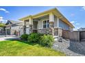 Home exterior with stone accents, a well-manicured lawn, and lush shrubbery at 3086 Kestrel St, Brighton, CO 80601