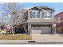 Two-story house with gray siding, a large driveway and landscaping at 4942 S Zephyr St, Littleton, CO 80123