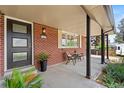 Inviting front porch with a black door, red brick, seating, and tasteful decor at 1475 Kingsbury Ct, Golden, CO 80401