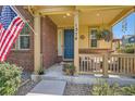 Inviting front porch with brick accents, blue door, decorative hanging plants, and cozy seating area at 1378 S Duquesne Ct, Aurora, CO 80018