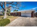 Charming brick home showcasing a well-manicured lawn, mature trees, and attached two car garage at 1302 S Cape Way, Lakewood, CO 80232