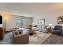 Spacious living room featuring plush seating, stylish decor, and sliding glass doors to a balcony at 3184 S Heather Gardens Way # 302, Aurora, CO 80014