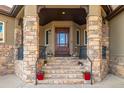 Charming front entrance with stone pillars, wood door with glass, and beautiful flower pots adorning the steps at 15501 Fairway Dr, Commerce City, CO 80022