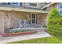Welcoming front porch with stone accents and comfortable rocking chairs at 9743 Chanteclair Cir, Highlands Ranch, CO 80126