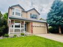 Charming two-story home featuring a front porch, manicured lawn, and an attached two-car garage at 21238 Snowshoe Ln, Parker, CO 80138